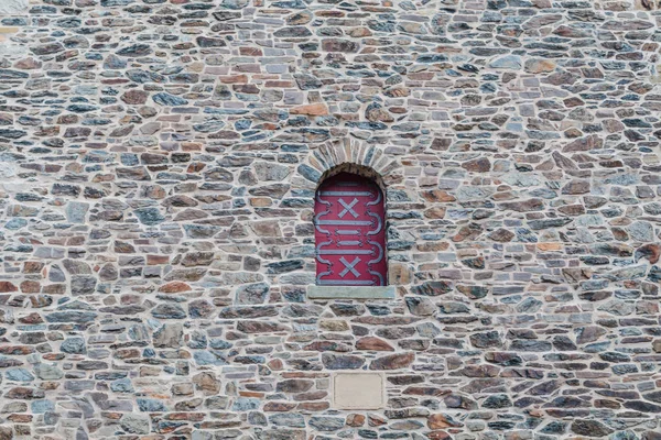 Part of an old fortress wall with a window and a frame in the form of a grid.