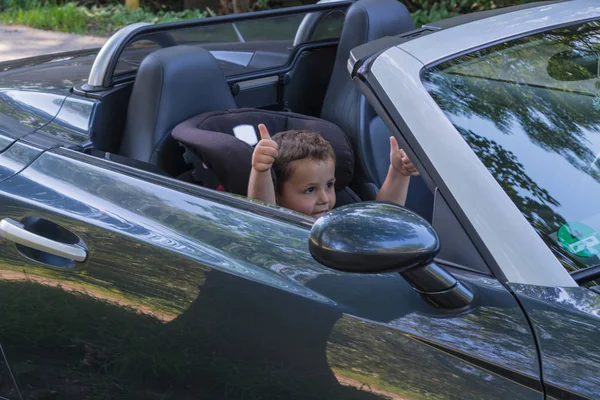 Happy Laughing Child Convertible Sits Car Child Seat Shows Thumbs — Stock Photo, Image