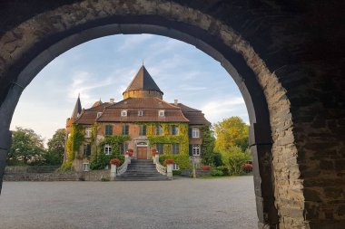 Sarmaşıkla kaplanmış eski bir kale. Kapı kemeriyle çekilmiş.