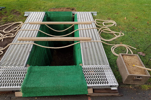 Open freshly excavated grave with green cover