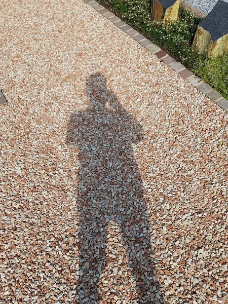 Una imagen de un fondo de guijarro marrón con sombras humanas —  Fotos de Stock