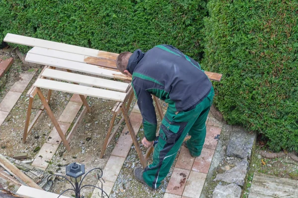 L'uomo accarezza vernice protettiva su mobili da giardino in legno . — Foto Stock