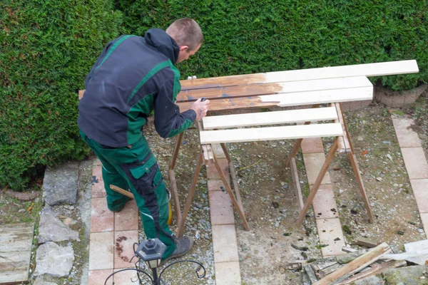 El hombre acaricia pintura protectora en muebles de jardín de madera . — Foto de Stock