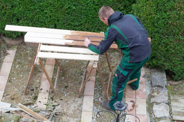 Man beroertes beschermende verf op houten tuinmeubelen. — Stockfoto