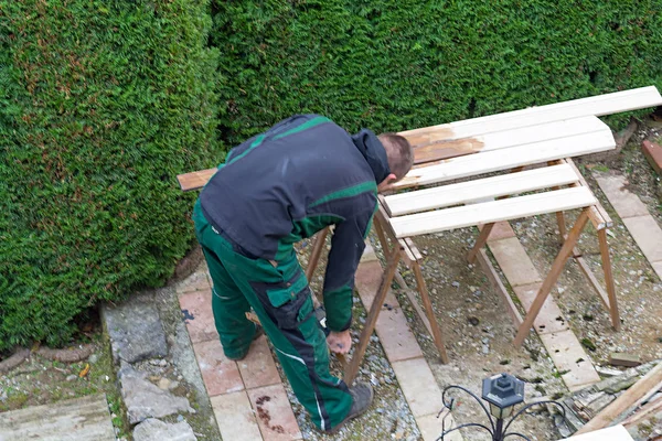男子在木制花园家具上抚摸保护漆. — 图库照片