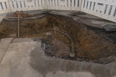 Mühendislik ve ısıtma sistemlerinin kurulumu üzerinde çalış. İki plastik boru, biri gaz borusu için sarı diğeri de elektrik hattı için siyah. Kum çukurundalar..