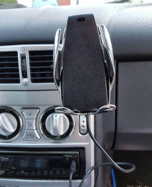 Benekli bir arabanın ön panelinde ekranı olan akıllı bir telefon.