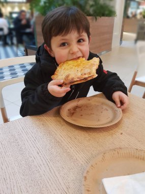 Restoranda pizza yiyen tatlı çocuk.