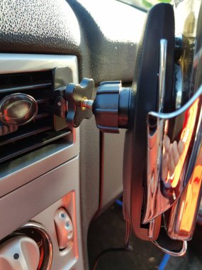 Benekli bir arabanın ön panelinde ekranı olan akıllı bir telefon.