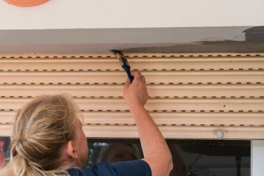 Pencere çerçevesini fırçalayan bir kadının arka planı.