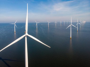 Yel değirmeni parkı Batı Hollanda, rüzgâr değirmeni türbini okyanusta mavi gökyüzü, yeşil enerji