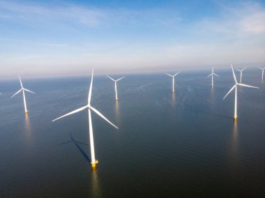 Yel değirmeni parkı Batı Hollanda, rüzgâr değirmeni türbini okyanusta mavi gökyüzü, yeşil enerji