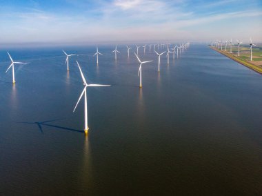 Yel değirmeni parkı Batı Hollanda, rüzgâr değirmeni türbini okyanusta mavi gökyüzü, yeşil enerji