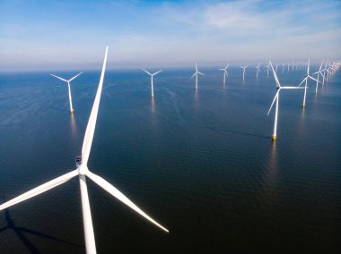 Yel değirmeni parkı Batı Hollanda, rüzgâr değirmeni türbini okyanusta mavi gökyüzü, yeşil enerji