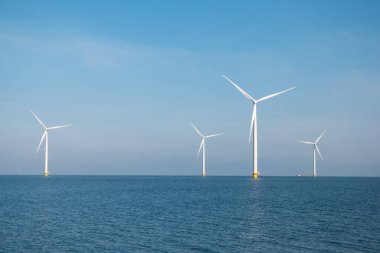 Yel değirmeni parkı Batı Hollanda, rüzgâr değirmeni türbini okyanusta mavi gökyüzü, yeşil enerji