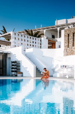 Santorini Yunanistan Oia, havuzda kısa süre yüzen gençler Santorini Adası 'nın Yunan kalderasına, Yunanistan' ın sonsuz havuzuna bakıyorlar.