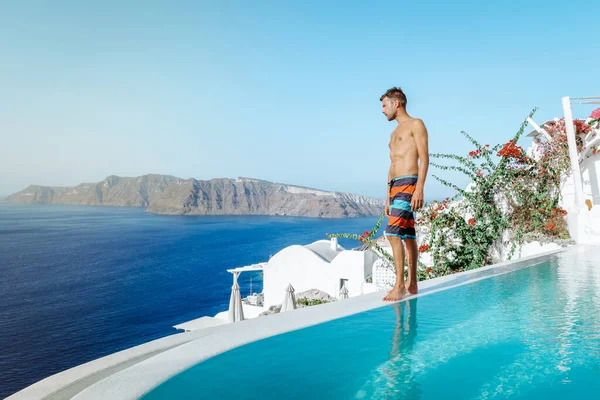 Санторіні Греція Оя, молоді чоловіки, які плавають у басейні і дивляться на кальдеру острова Санторіні, на безкінечний басейн Греції. — стокове фото