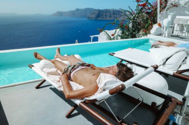 Santorini Yunanistan Oia, havuzda kısa süre yüzen gençler Santorini Adası 'nın Yunan kalderasına, Yunanistan' ın sonsuz havuzuna bakıyorlar.