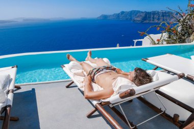 Santorini Yunanistan Oia, havuzda kısa süre yüzen gençler Santorini Adası 'nın Yunan kalderasına, Yunanistan' ın sonsuz havuzuna bakıyorlar.