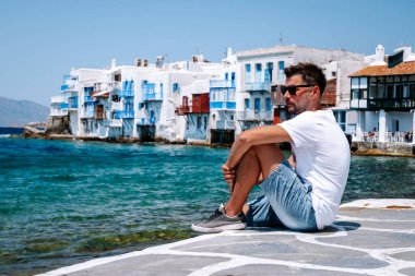 Yunan adası Mykonos 'ta tatilde olan genç adam, Mykonos Adası' ndaki küçük Venedik köyünde dinlenen adamlar.