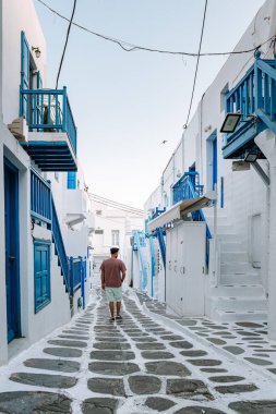 Yunan adası Mykonos 'ta tatilde olan genç adam, Mykonos Adası' ndaki küçük Venedik köyünde dinlenen adamlar.