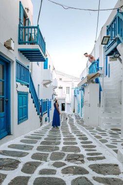 Mykonos Yunanistan, Yunan Adası Mykonos 'ta tatil yapan çift, küçük Venedik Mykonos' un beyaz caddelerinde giyinmiş kız ve erkek.