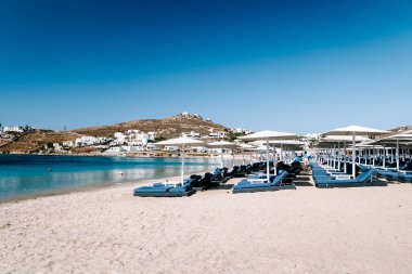 Mykonos Yunanistan plajında şemsiyeli tropik plaj sandalyeleri