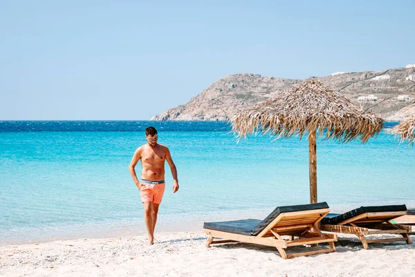 Mladý muž v plavat krátký na pláži Mykonos Řecko, chlap na pláži židle na pláži Mykonos — Stock fotografie