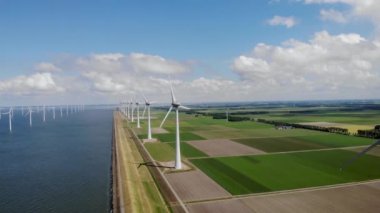 Yel değirmeni parkı Batı Hollanda, rüzgâr değirmeni türbini okyanusta mavi gökyüzü, yeşil enerji