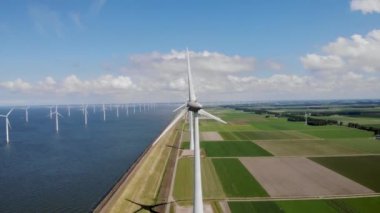 Yel değirmeni parkı Batı Hollanda, rüzgâr değirmeni türbini okyanusta mavi gökyüzü, yeşil enerji