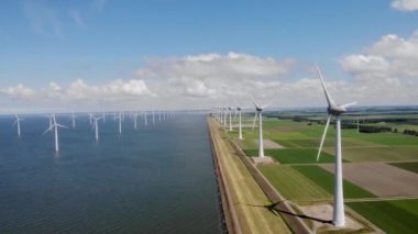 Yel değirmeni parkı Batı Hollanda, rüzgâr değirmeni türbini okyanusta mavi gökyüzü, yeşil enerji