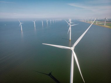 Yel değirmeni parkı Batı Hollanda, okyanusta mavi gökyüzü olan rüzgar türbini, yeşil enerji, küresel ısınma kavramı