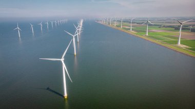 Yel değirmeni parkı Batı Hollanda, rüzgâr değirmeni türbini okyanusta mavi gökyüzü, yeşil enerji
