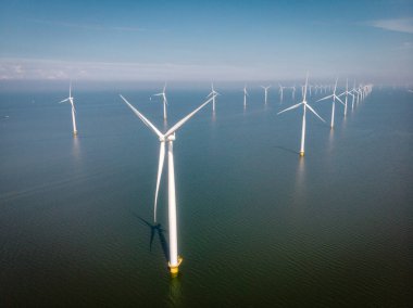 Yel değirmeni parkı Batı Hollanda, rüzgâr değirmeni türbini okyanusta mavi gökyüzü, yeşil enerji