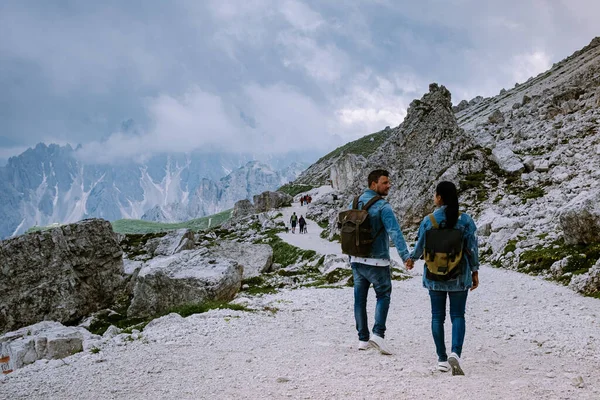 Casal caminhadas nas dolomitas italianas durante o tempo nebuloso com nuvens, vista deslumbrante para os picos de Tre Cime em Dolomites, Itália — Fotografia de Stock