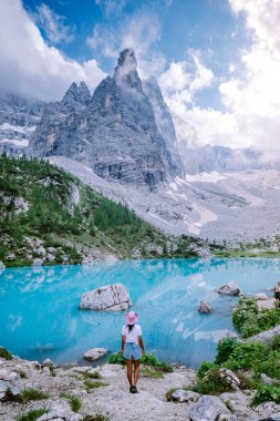 İtalyan Dolomitleri 'nde mavi yeşil göle yürüyüş yapan bir kadın, Dolomitler' de Güzel Sorapis Gölü Lago di Sorapis, İtalya 'da popüler bir seyahat merkezi.