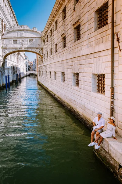 Пара во время городской поездки в Венецию, влюбленная пара в отпуске в Венеции, Италия Millennials сидя на канале с гондолами — стоковое фото