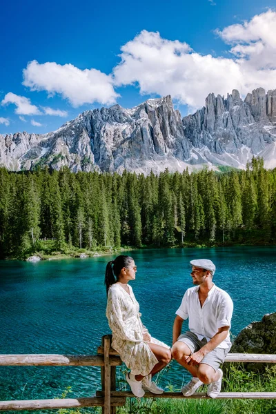 Пара посещает озеро hte bleu в Доломитах Италия, Карецца озеро Лаго-ди-Карецца, Карерзе с горой Латемар, Больцано провинции, Южный Тироль, Италия. Пейзаж озера Карецца или Карерзе и Доломиты — стоковое фото
