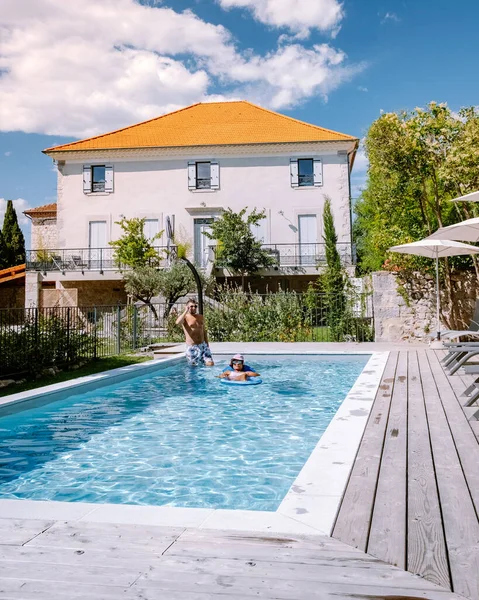 French vacation home with wooden deck and swimming pool in the Ardeche France. Couple relaxing by the pool with wooden deck during luxury vacation at an holiday home in South of France