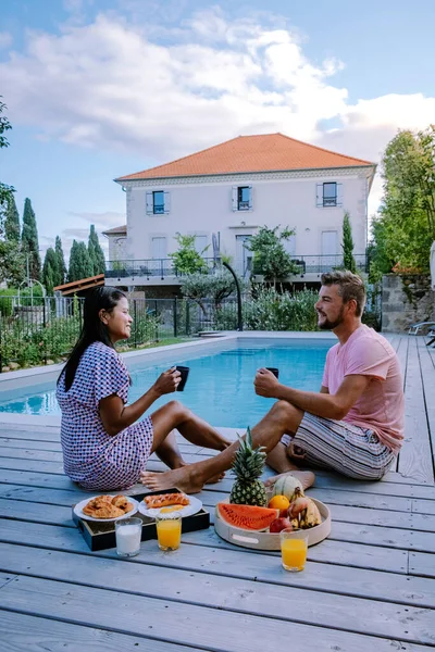 French vacation home with wooden deck and swimming pool in the Ardeche France. Couple relaxing by the pool with wooden deck during luxury vacation at an holiday home in South of France