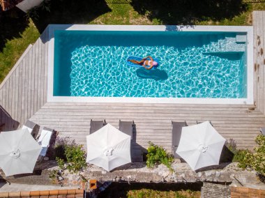 Oteldeki havuzda iki kişi yüzüyor. Yukarıdan bakıldığında, birkaç erkek ve kadın Ardeche Fransa 'da lüks tatil evlerinde yüzüyorlar.