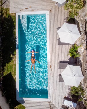 Oteldeki havuzda iki kişi yüzüyor. Yukarıdan bakıldığında, birkaç erkek ve kadın Ardeche Fransa 'da lüks tatil evlerinde yüzüyorlar.