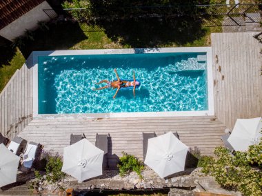 Oteldeki havuzda iki kişi yüzüyor. Yukarıdan bakıldığında, birkaç erkek ve kadın Ardeche Fransa 'da lüks tatil evlerinde yüzüyorlar.