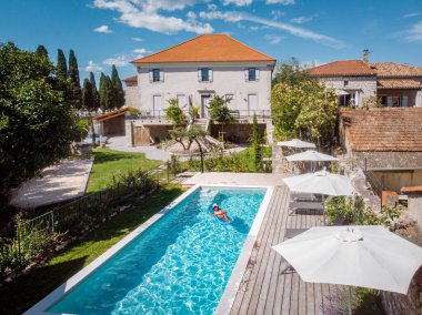Oteldeki havuzda iki kişi yüzüyor. Yukarıdan bakıldığında, birkaç erkek ve kadın Ardeche Fransa 'da lüks tatil evlerinde yüzüyorlar.