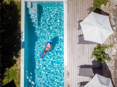 Oteldeki havuzda iki kişi yüzüyor. Yukarıdan bakıldığında, birkaç erkek ve kadın Ardeche Fransa 'da lüks tatil evlerinde yüzüyorlar.