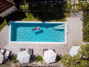 Oteldeki havuzda iki kişi yüzüyor. Yukarıdan bakıldığında, birkaç erkek ve kadın Ardeche Fransa 'da lüks tatil evlerinde yüzüyorlar.