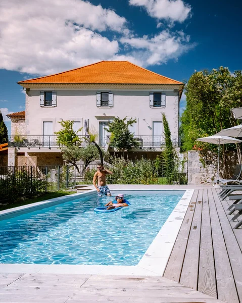 French vacation home with wooden deck and swimming pool in the Ardeche France. Couple relaxing by the pool with wooden deck during luxury vacation at an holiday home in South of France