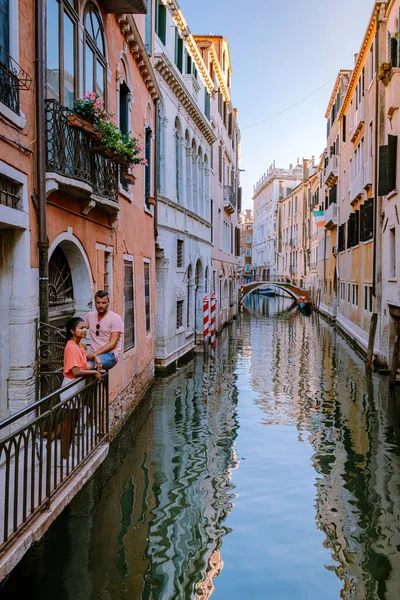 Пара мужчин и женщин во время поездки в Венецию Италия, красочные улицы с каналами Венеция — стоковое фото