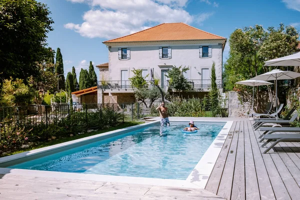 French vacation home with wooden deck and swimming pool in the Ardeche France. Couple relaxing by the pool with wooden deck during luxury vacation at an holiday home in South of France