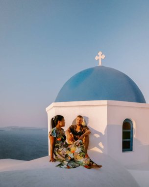 Santorini Yunanistan, genç çift güneş doğarken mavi kubbe kilisesi ve beyazlatılmış Oia Santorini köyünün gündoğumunu izlemek için Santorini Adası 'nda lüks bir tatile çıktılar.